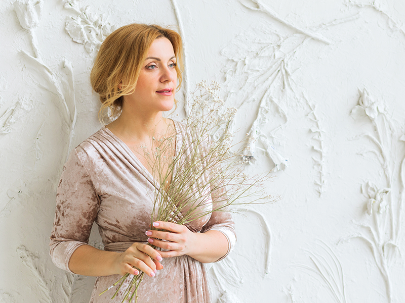 a woman wearing an elegant dress while holding a dried flowers